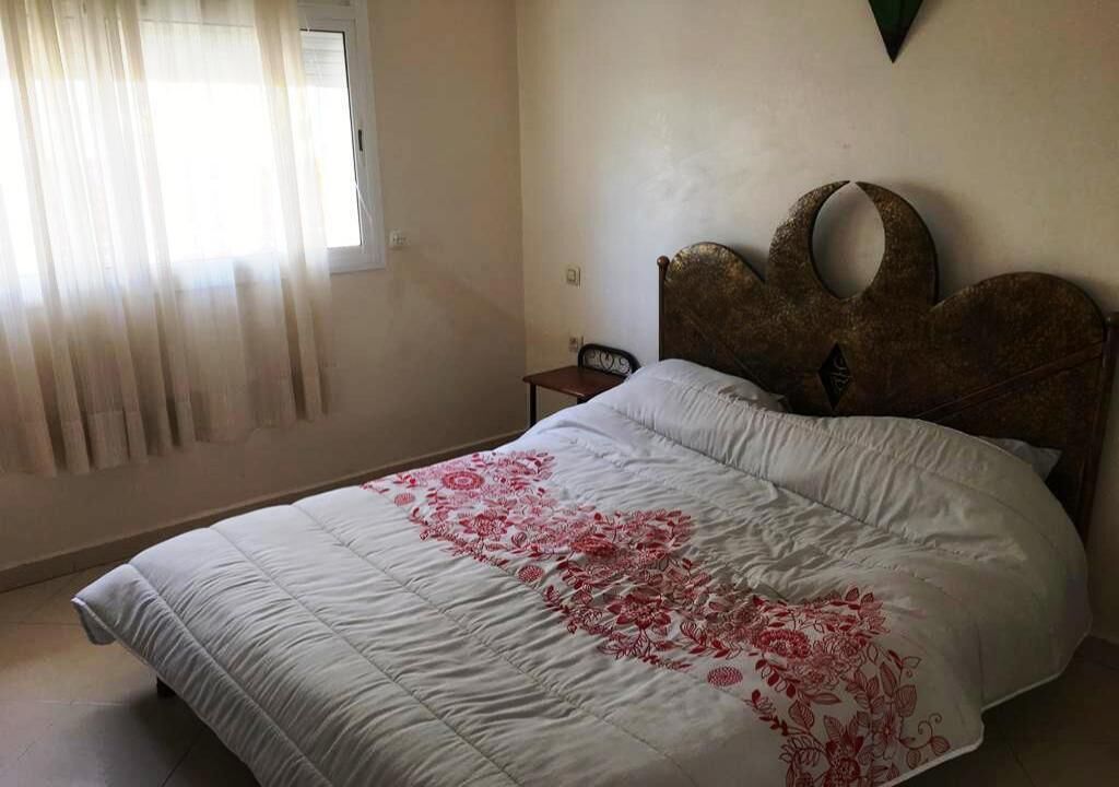 Ein Schlafzimmer mit einem Bett, einem Nachttisch und einem Fenster mit Vorhängen.