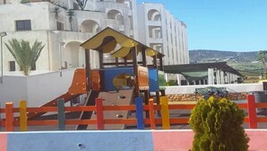 Ein Spielplatz mit bunter Spielausstattung und einem Zaun.