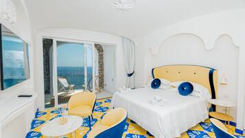 A hotel room with a bed, a chair, a small table, and a balcony with a view.