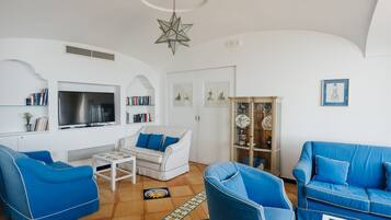 A living room with a white sofa, blue armchairs, a coffee table, a TV, and a decorative star hanging from the ceiling.