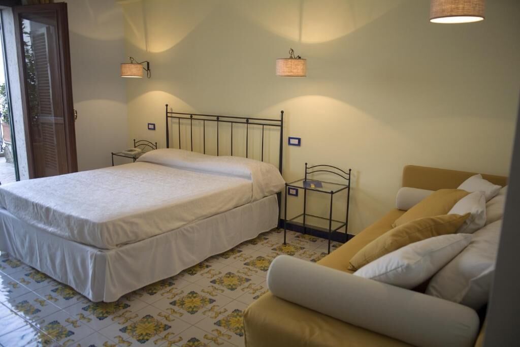 A bedroom with a bed, bedside tables, a chair, and a sofa.