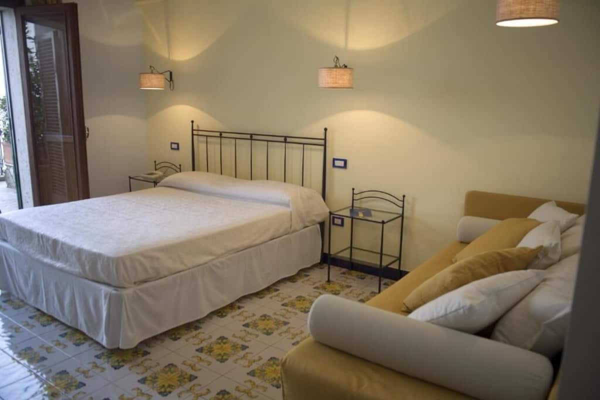 A bedroom with a bed, bedside tables, a chair, and a sofa.