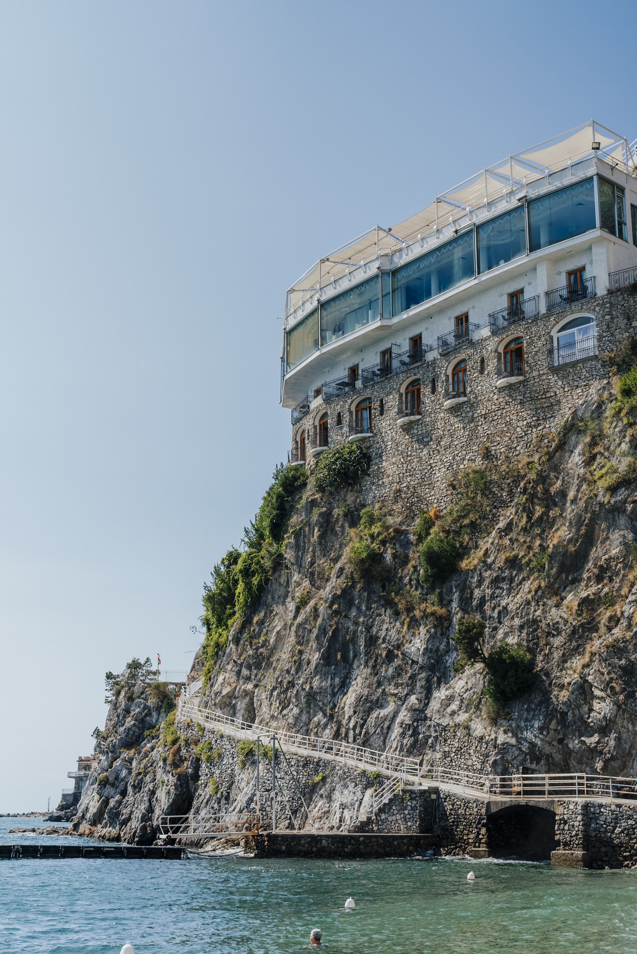 Un edificio sul lungomare con una scala che conduce a un balcone, affacciato sul mare.