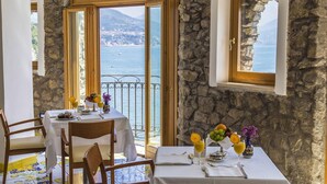 A dining area with a table set for two, overlooking a coastal view. - Hotel Cetus (Cetara)