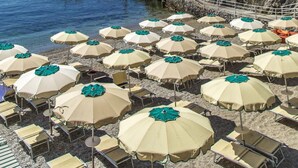 A coastal hotel with a cliffside terrace, beach umbrellas, and lounge chairs. - Hotel Cetus (Cetara)
