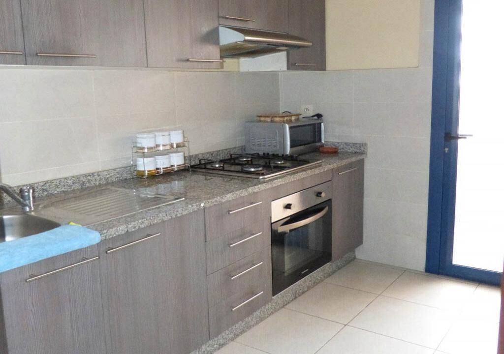 Una cocina con gabinetes grises, una estufa a gas, un microondas y un horno empotrado.