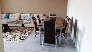 A dining area with a table and chairs, a patterned rug, and a sofa with cushions.
