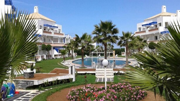 Et resort med swimmingpool, palmer og en blomsterhave.