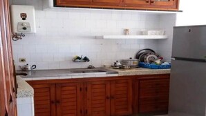 A kitchen with wooden cabinets, a stainless steel sink, and a refrigerator. - Apartment in Assilah 4396 (Asilah)
