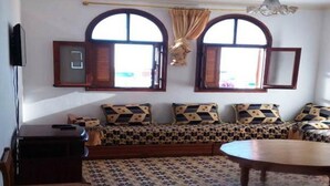 A room with a sofa set, a wooden table, and a patterned floor. - Apartment in Assilah 4396 (Asilah)