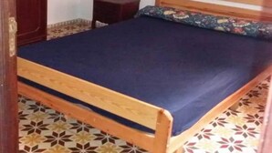A single bed with a wooden frame and a blue mattress in a room with patterned floor tiles. - Apartment in Assilah 4396 (Asilah)