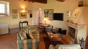 A cozy living room with a sofa, a fireplace, and a television. - Splendid historical residence in the Lazio Maremma (Tessennano)