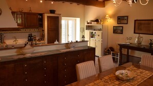 A kitchen with wooden cabinets, a central island, and a dining area with a table and chairs. - Splendid historical residence in the Lazio Maremma (Tessennano)