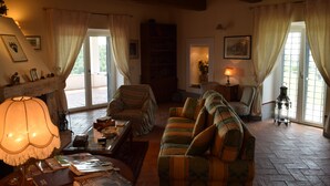 A cozy living room with a fireplace, a sofa, a chair, and a lamp. - Splendid historical residence in the Lazio Maremma (Tessennano)