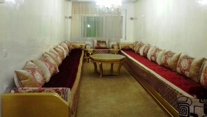 A room with a long sofa set, a small table, and a chandelier. - Apartment in Martil 4421 (Martil)