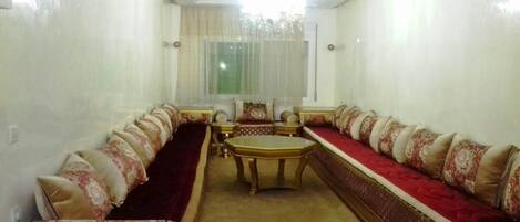 A room with a long sofa set, a small table, and a chandelier.