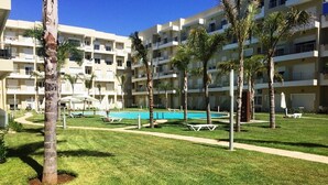A hotel courtyard with a swimming pool, palm trees, and outdoor seating areas. - Beautiful apartment in Bouznika 4475 (Bouznika)