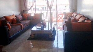 A living room with a sofa set, a coffee table, and a view of the outside balcony. - Beautiful apartment in Bouznika 4475 (Bouznika)