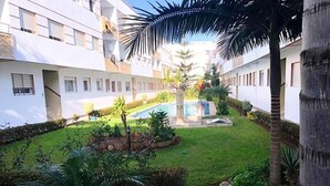 Ein Innenhof mit Schwimmbad, Palmen und einem gepflegten Rasen.
