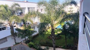 Ein Innenhof mit Palmen, einem Swimmingpool und einer gemusterten Steinsitzbank.