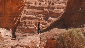 A natural rock arch formation with a person standing in the foreground.