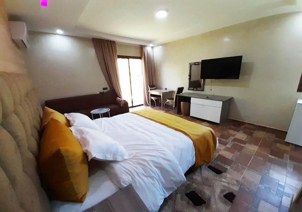 A hotel room with a bed, a desk, a chair, a television, and a window with curtains.