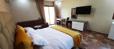 A hotel room with a bed, a desk, a chair, a television, and a window with curtains.
