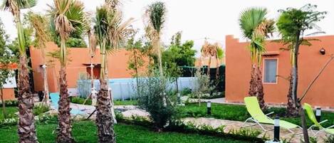 A garden with palm trees, a swimming pool, and outdoor seating.