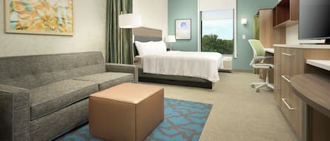 A hotel room with a bed, a sofa, a desk, and a television.