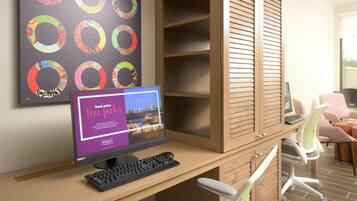 A hotel room with a desk, computer, and a large window.