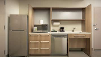 A compact kitchen with a refrigerator, microwave, coffee maker, and dishwasher.