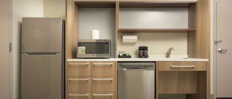 A compact kitchen with a refrigerator, microwave, coffee maker, and dishwasher.