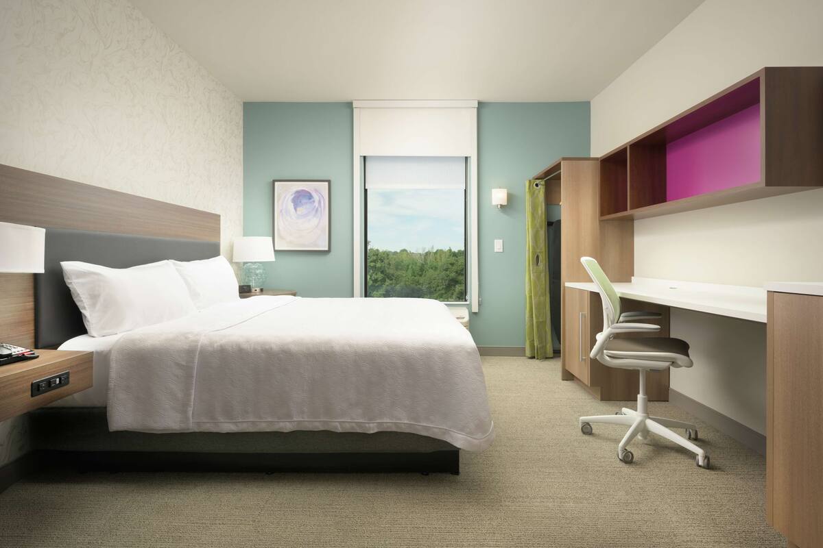 Ein Hotelzimmer mit Bett, Schreibtisch und Stuhl.