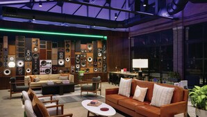 Una sala de estar moderna con un sofá, sillones, una mesa de centro y una pared decorada con varios altavoces.
