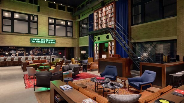 Amplia sala de estar con diversas opciones de asiento, un bar y una escalera que sube a un nivel superior.