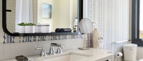 A modern bathroom with a double sink, a large mirror, and a toilet.