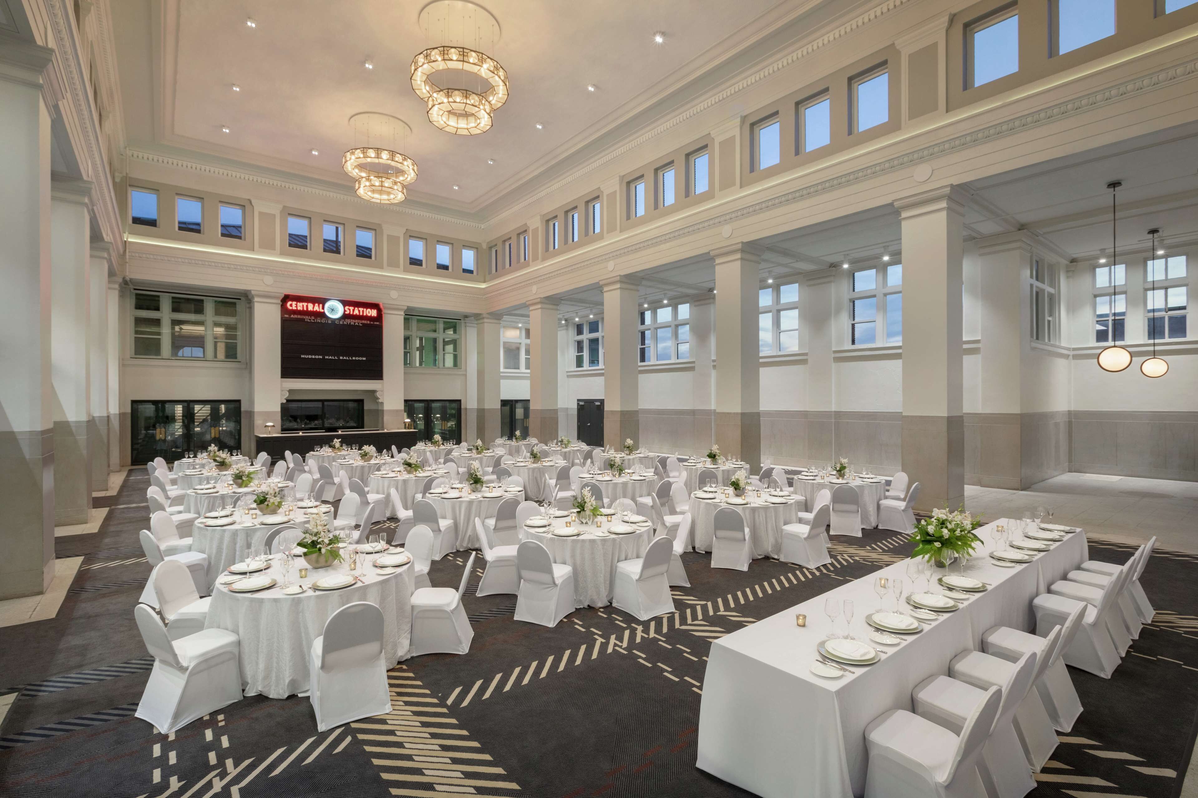 Un amplio salón de banquetes con varias mesas redondas dispuestas para comer, con manteles blancos y sillas.