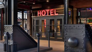 Entrada de hotel con un llamativo letrero que dice 'HOTEL', una escalera y una estructura metálica.