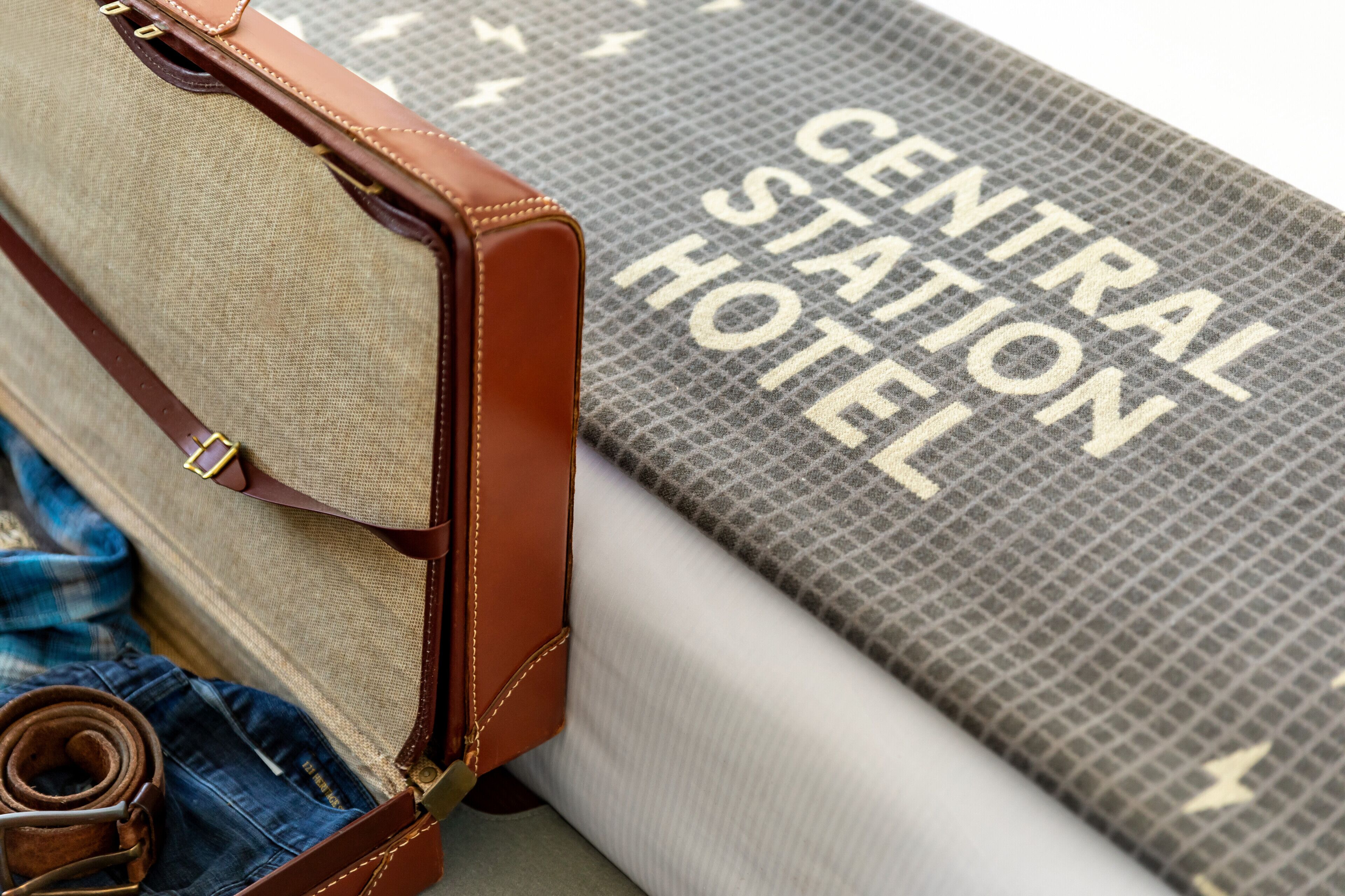 A suitcase with a brown leather exterior and a rolled-up pair of jeans inside.