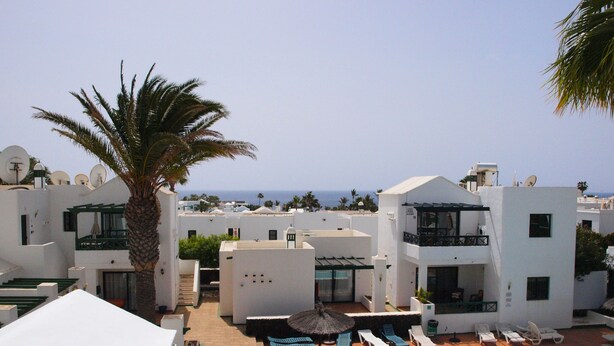 A resort with white buildings, a pool, and a view of the sea. - Modern, upstairs apartment with sea view, Wifi, Air Con and U.K. TV (Puerto del Carmen)