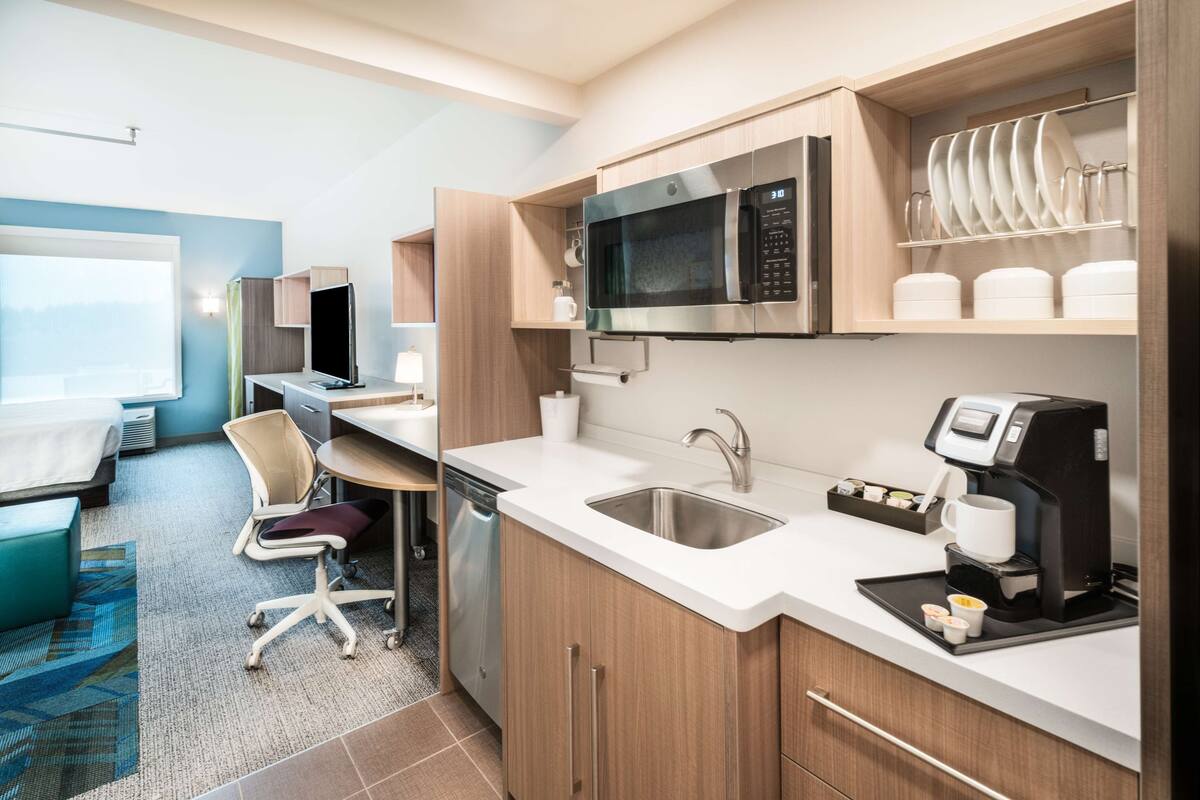 A modern kitchen with a microwave, coffee machine, and dish rack.