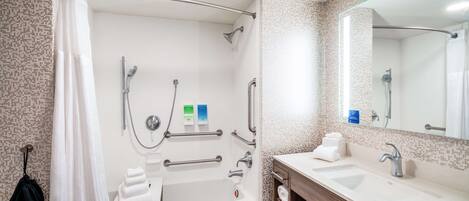 A modern bathroom with a bathtub, shower, and dual sinks.