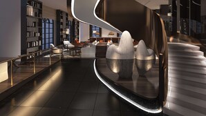 Un interior moderno con una escalera curva, una zona de estar con sofás y mesas, y una biblioteca con estanterías.