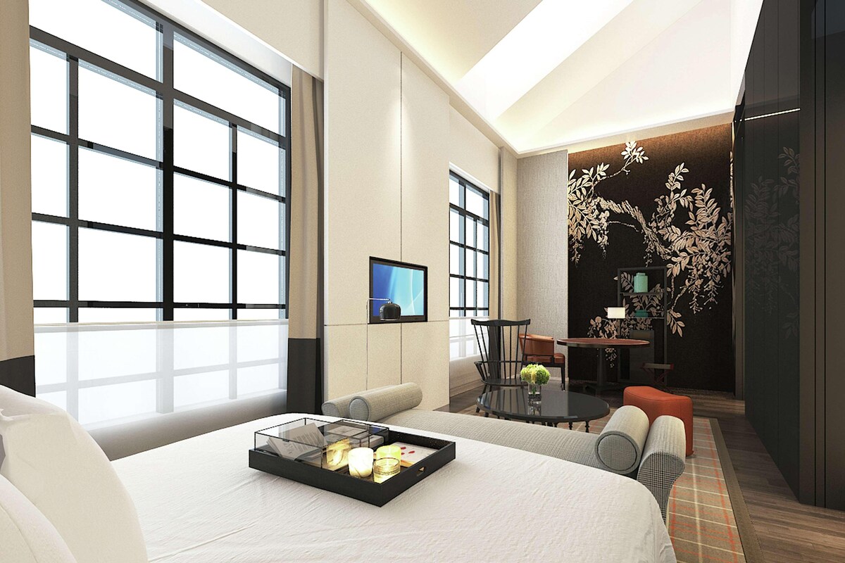 Een moderne hotelkamer met een groot bed, een televisie, een zithoek en een decoratieve wand.