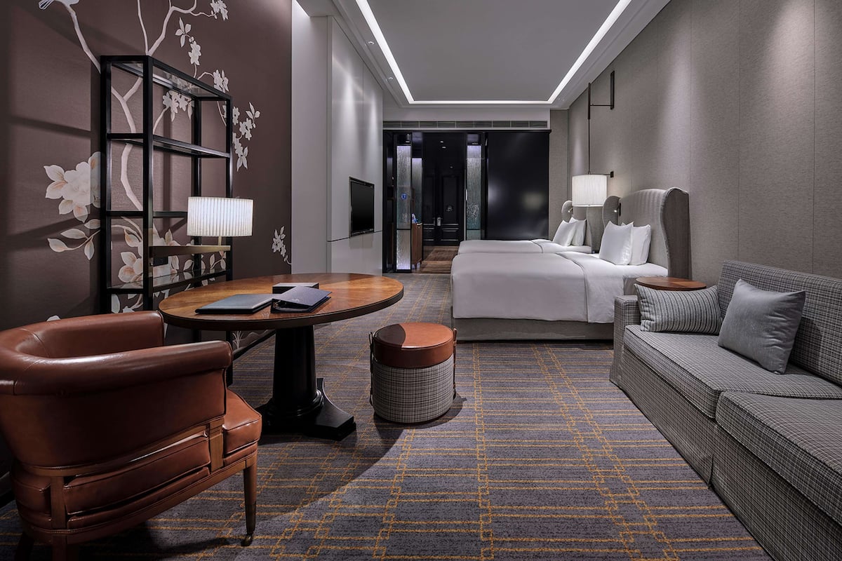 Ein modernes Hotelzimmer mit einem Bett, einer Couch, einem Schreibtisch und einem Sessel.