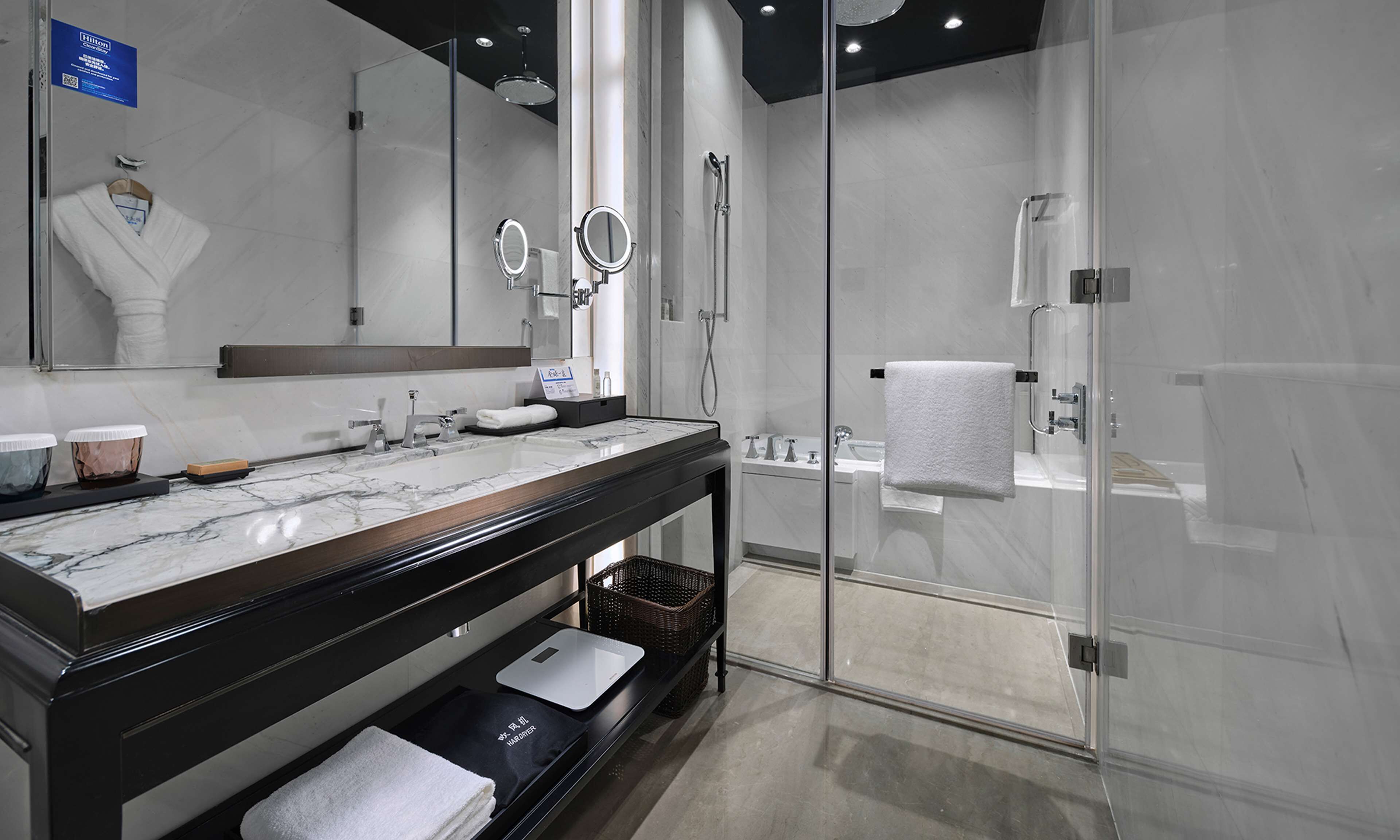 A modern bathroom with a marble vanity, a glass shower enclosure, and a large mirror.