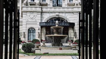A grand entrance with a central fountain, flanked by symmetrical columns and a classical building facade.