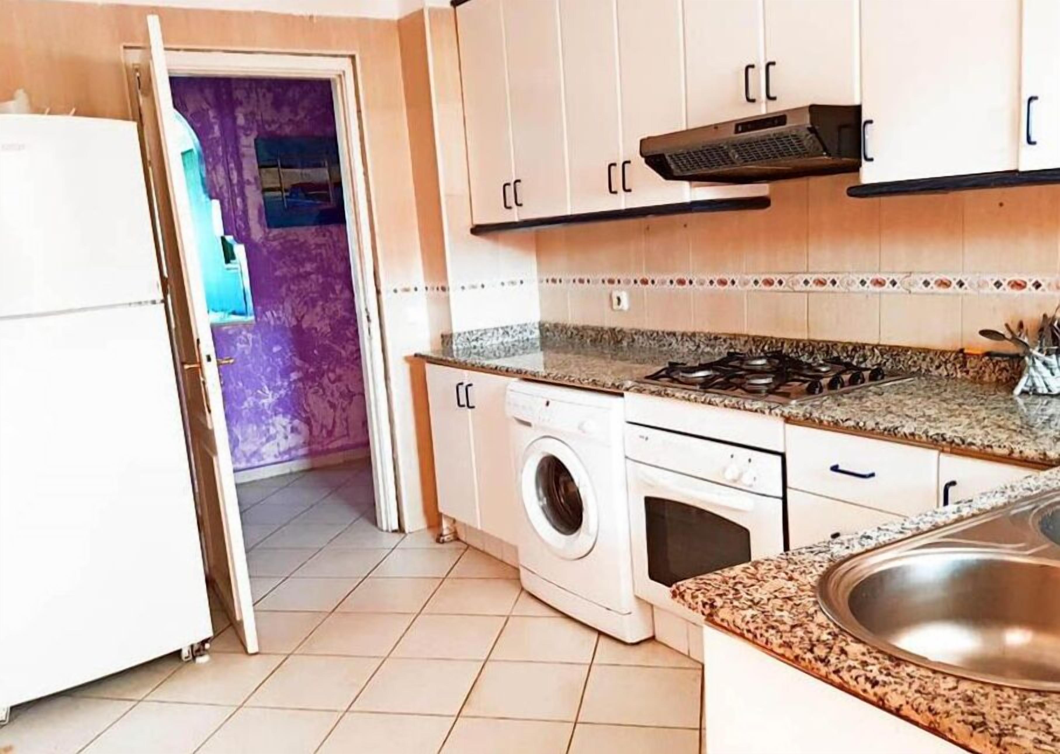 A compact kitchen with a washing machine, a stove, and a sink.