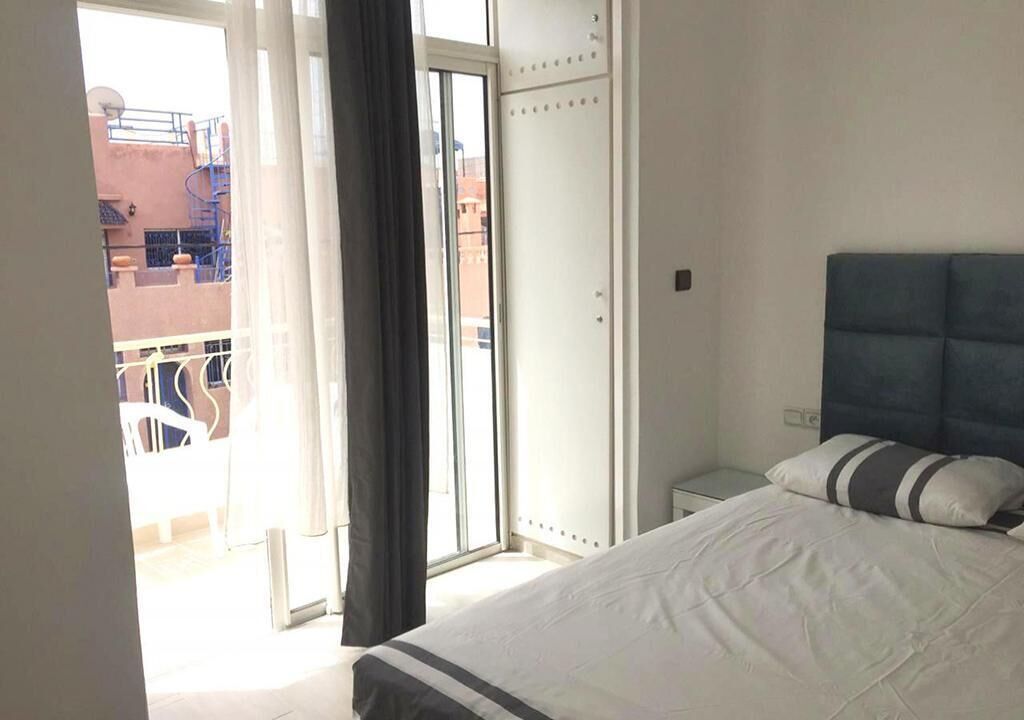 A bedroom with a bed, a wardrobe, and a view of the outside balcony.