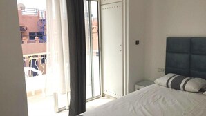 Een slaapkamer met een bed, een kledingkast en uitzicht op het balkon.